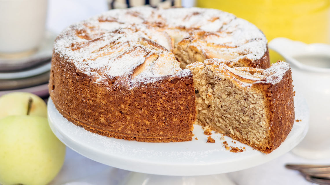 Apfel-Haselnusskuchen auf weißer Kuchenplatte. | © Kathrin Salzwedel / Ramin Madani