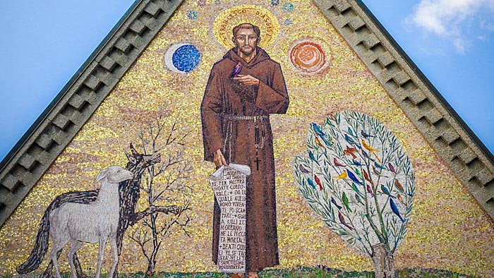 Dreieckiges Mosaik, das den heiligen Franziskus von Assisi darstellt, wie er gen Himmel deutet. | © shutterstock.com