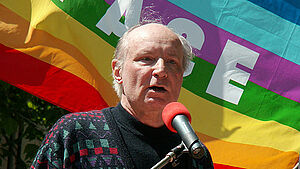 Eugen Drewermann am Mikrofon vor einer Peace-Fahne