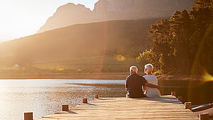 Sitzendes Rentnerpaar am Steg mit Blick auf den See.