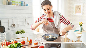 Frau bereitet das Mittagessen in der Küche zu. | © Yuganov Konstantin/shutterstock.com