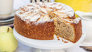 Apfel-Haselnusskuchen auf weißer Kuchenplatte. | © Kathrin Salzwedel / Ramin Madani