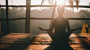 Frau in Medidation bei Sonnenaufgang | © Jared Rice, unsplash