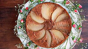 Birnenkuchen auf weißem Teller mit Blumen dekoriert. | © Christiane Kösler