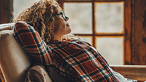 Frau, die gemütlich, Arme hinter dem Kopf verschränkt, im Sessel sitzt. | © simona pilolla 2, shutterstock.com