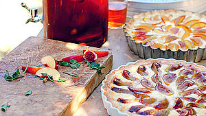 Tartes mit Feigen und Pfirsichen, daneben Brett mit geschnittenen Pfirsichen. | © Sophie Hansen