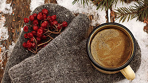 Handschuhe, Tannenzweig und Kaffeetasse auf verschneitem Holz. | © pixabay.com