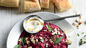 Rote-Bete-Hummus im Teller, Löffel mit Joghurt und Baguette. | © Kerouédan/Photocuisine