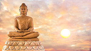 Buddha aus Stein vor Hintergrund eines Sonnenuntergangs. | © shutterstock.com