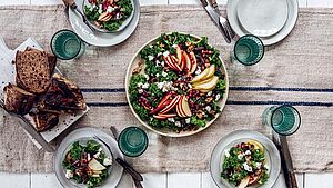 Gedeckter Tisch mit gefüllten Tellern mit Grünkohlsalat. | © Julia Cawley