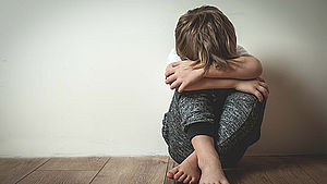 Trauriger Junge sitzt auf Boden und versteckt sein Gesicht in den Armen. | © Sharomka/shutterstock.com