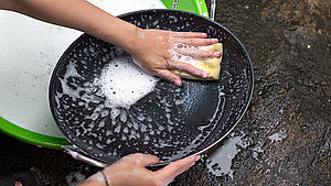 Zwei Hände zu sehen, die eine Pfanne spülen. | © LN_PHOTO, shutterstock.com