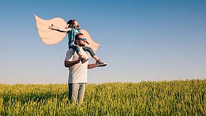 Vater mit Sohn auf den Schultern in einem Feld im Sommer. | ©Sunny studio, shutterstock.com