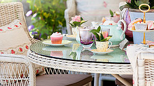 Gedeckter Tisch mit Korbstühlen für den Nachmittagstee und Kuchen im Garten. | © Simon Bratt/shutterstock.com