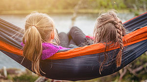 Zwei Mädchen liegen in der Hängematte und schauen auf einen See. | © Janko Ferlic, unsplash.comZwei Mädchen liegen in der Hängematte und schauen auf einen See. | © Janko Ferlic, unsplash.com